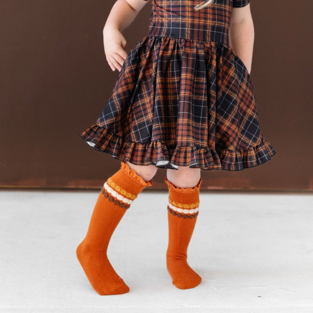 little girl in brown and black plaid twirl dress with harvest lace top knee highs for Thanksgiving