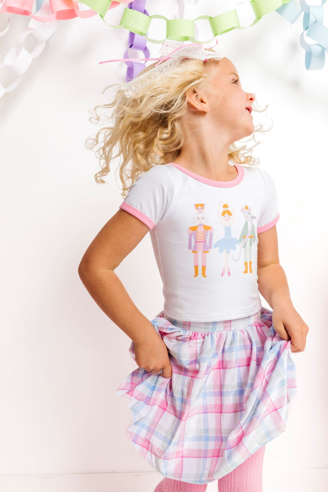 little girl twirling in Nutcracker print top and matching pastel plaid velvet skirt for winter