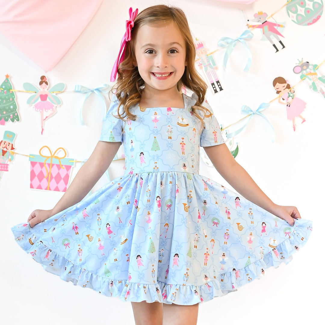 little girl twirling in blue nutcracker christmas dress and matching pink bow