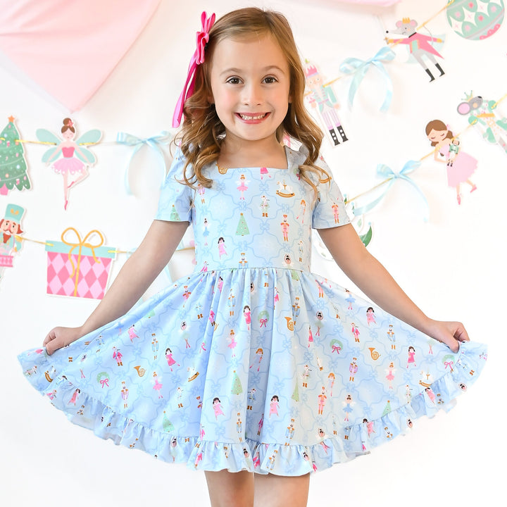 little girl twirling in blue nutcracker christmas dress and matching pink bow