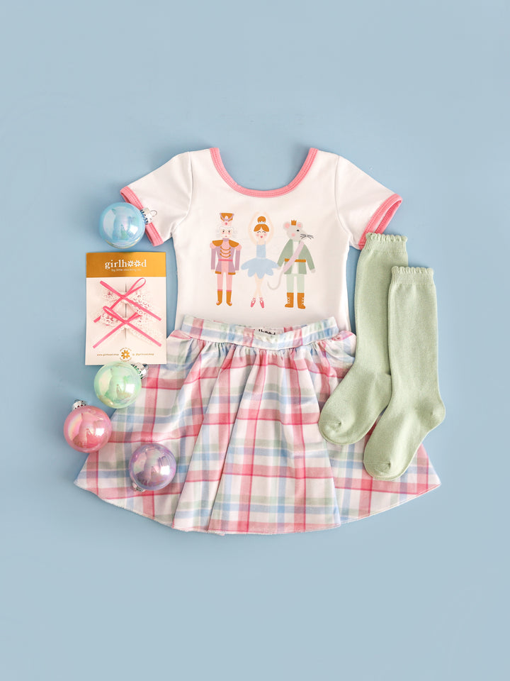 girls Nutcracker inspired outfit featuring white fitted top with Nutcracker characters paired with matching pastel plaid velvet skirt and mint green socks