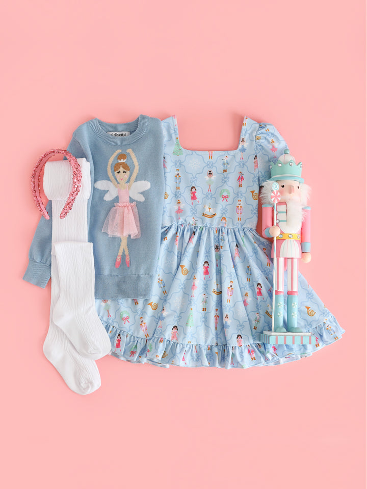 girls' nutcracker inspired Christmas outfit featuring blue nutcracker print twirl dress, matching blue sugarplum fairy sweater, white crochet tights and sparkly pink headband