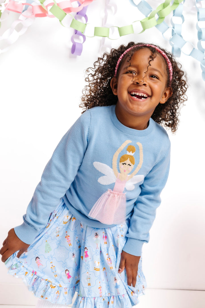little girl in blue nutcracker print twirl dress paired with blue pullover sweater featuring ballerina fairy wearing sparkly tutu