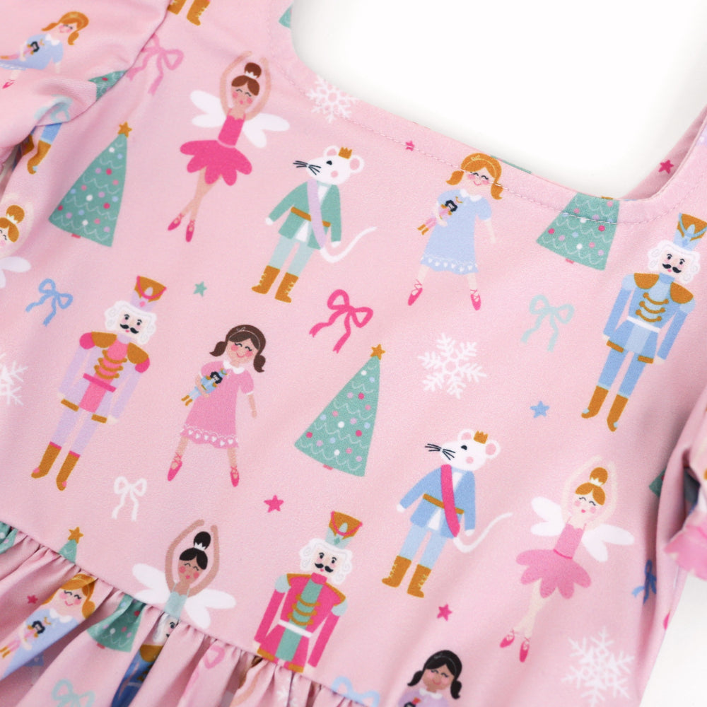 closeup of square neckline on little girls pastel pink nutcracker print dress for Christmas