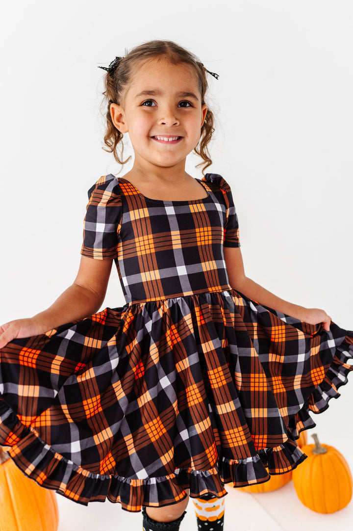 girl wearing black and orange plaid twirl dress