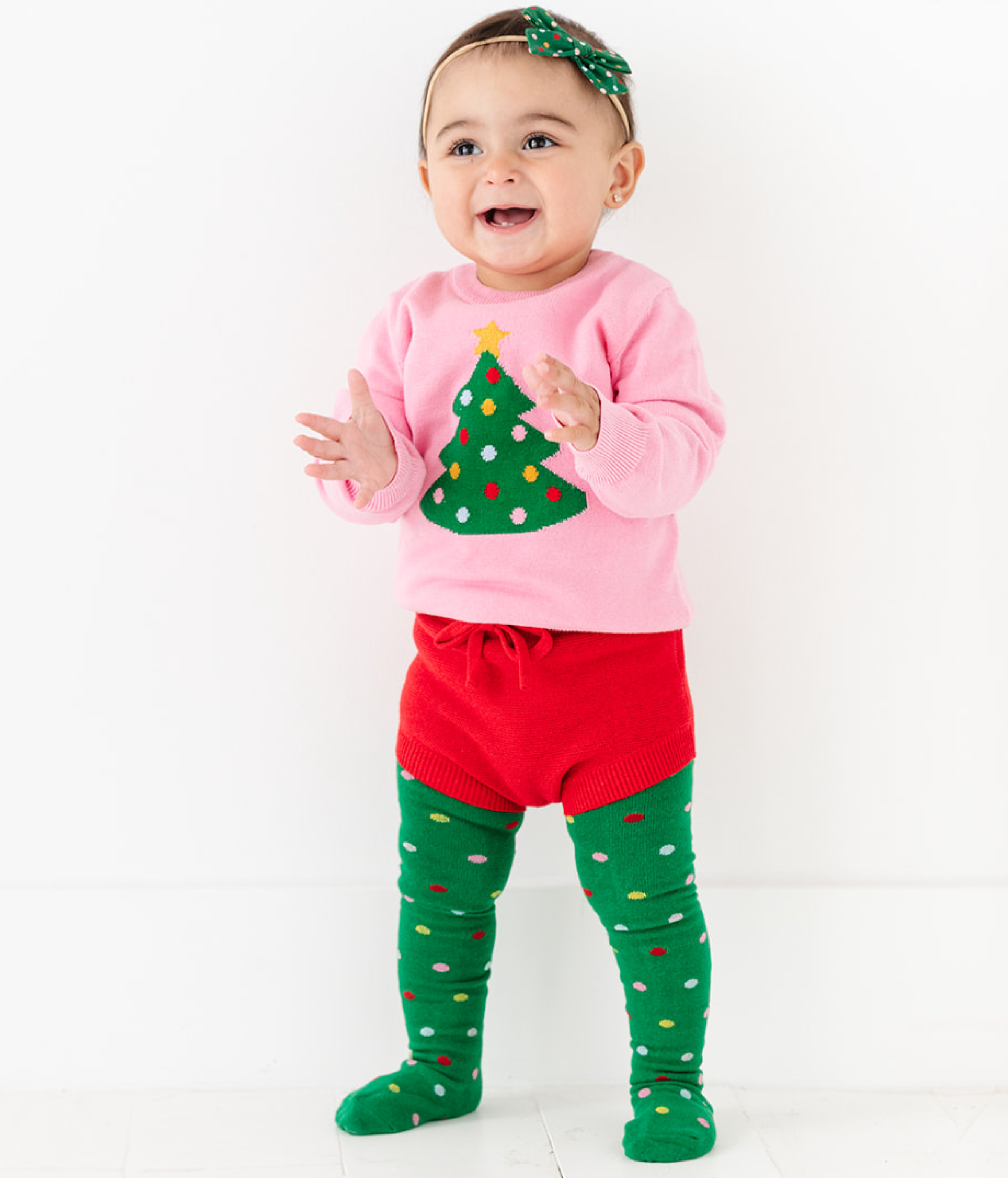 baby girl in pink and green Christmas tree pullover sweater with matching knit bloomers, polka dot tights and bow