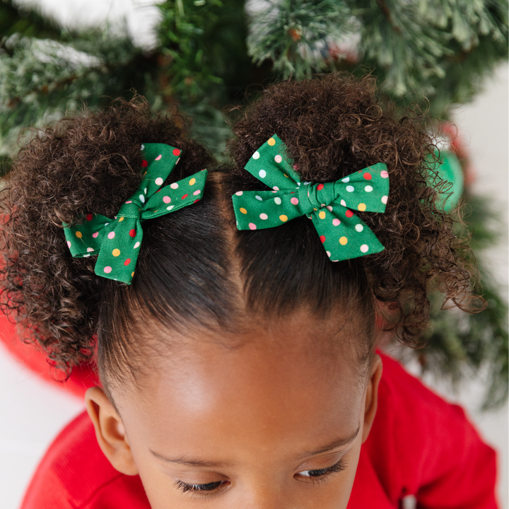 little girl in green Christmas pigtail bows with multicolored polka dots 