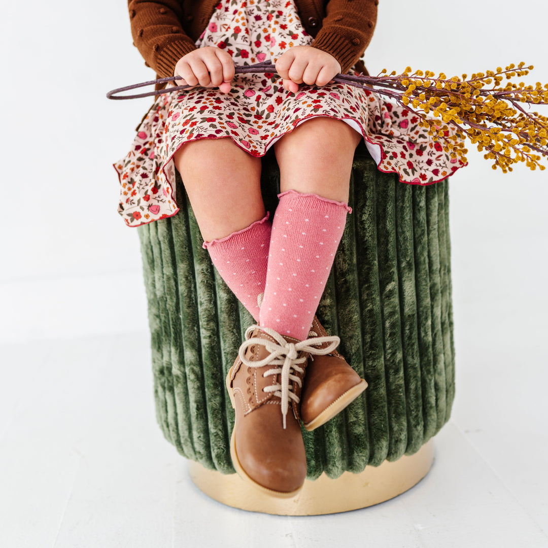 young girl holding fall foliage in mauve lettuce trim knee socks with ivory dot design paired with fall floral dress and brown sweater