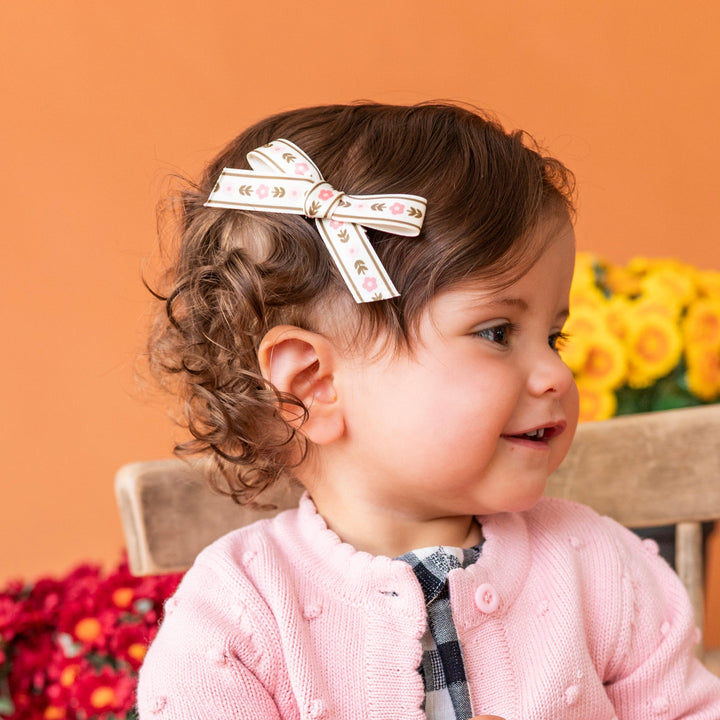 baby girl with rose and olive floral pigtail clip paired with matching pink bubble sweater