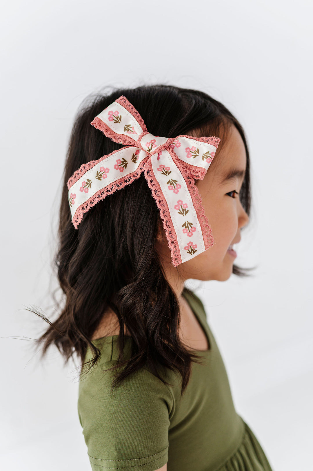 young girl in fall green dress paired with ivory and pink floral hair bow with pink lace trim