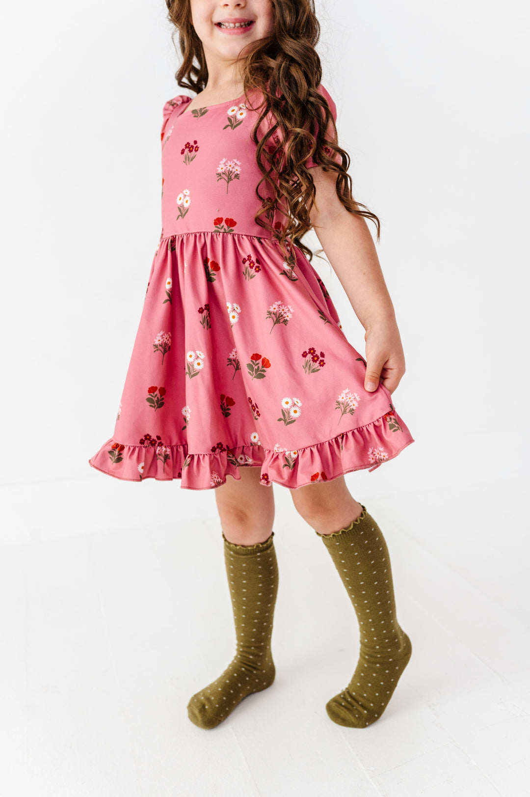 young girl wearing rosy pink twirl dress with fall floral design paired with olive lettuce trim knee socks with ivory dots