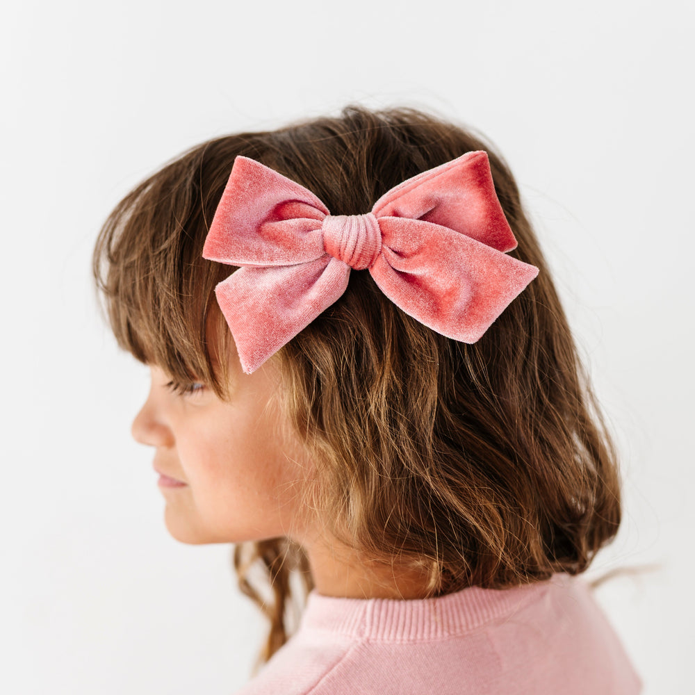 young girl wearing pink velvet hair bow on clip paired with light pink cotton knit sweater