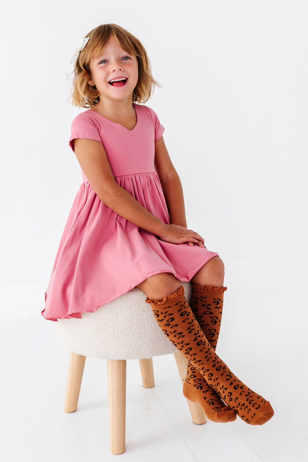 girl wearing pink twirl dress with leopard print knee high socks