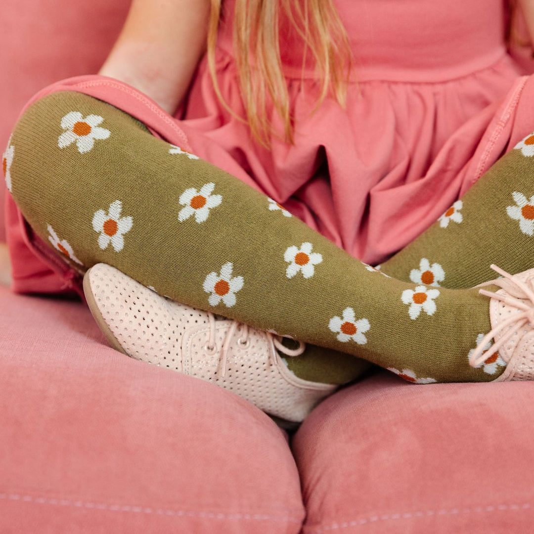 little girl sitting in pink dress and olive green floral tights