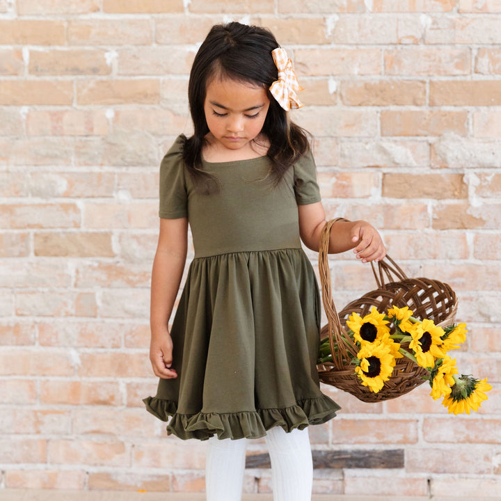 little girl wearing olive green cotton twirl dress holding basket of sunflowers