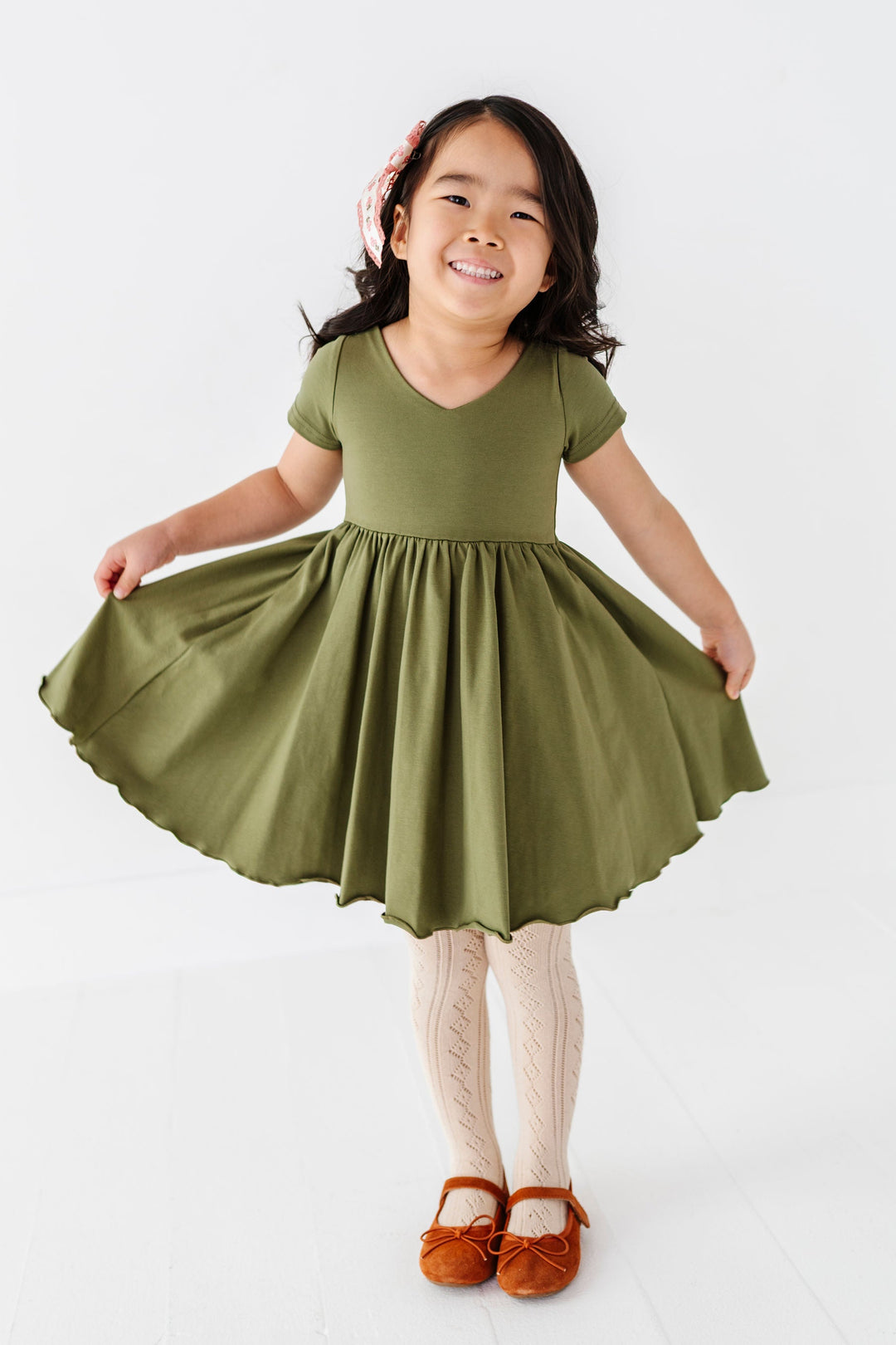 girl wearing olive green short sleeve twirl dress with cream pointelle tights