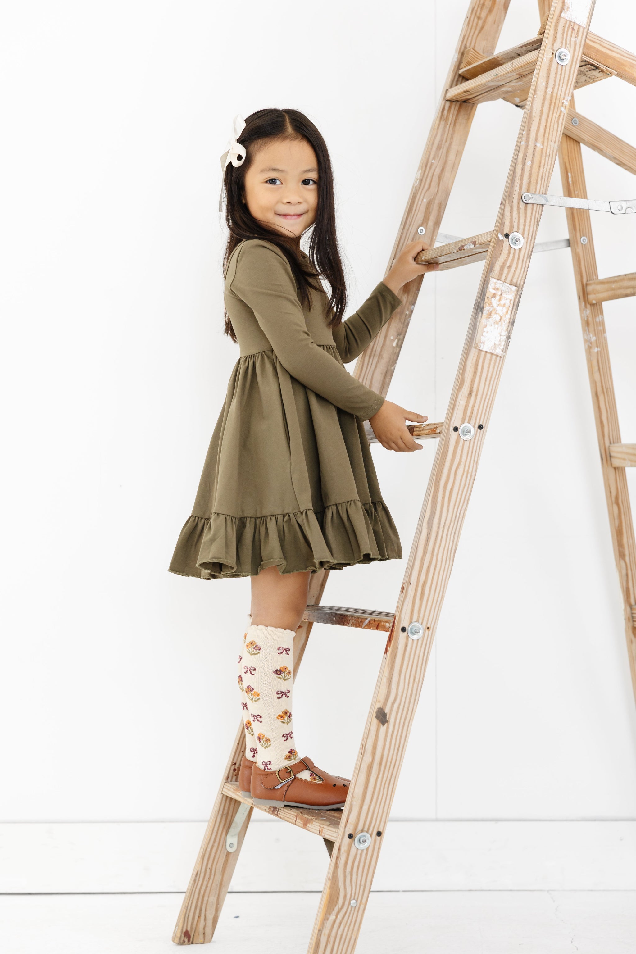 little girl in olive green long sleeve cotton blend twirl dress and matching cream floral knee highs with scalloped trim