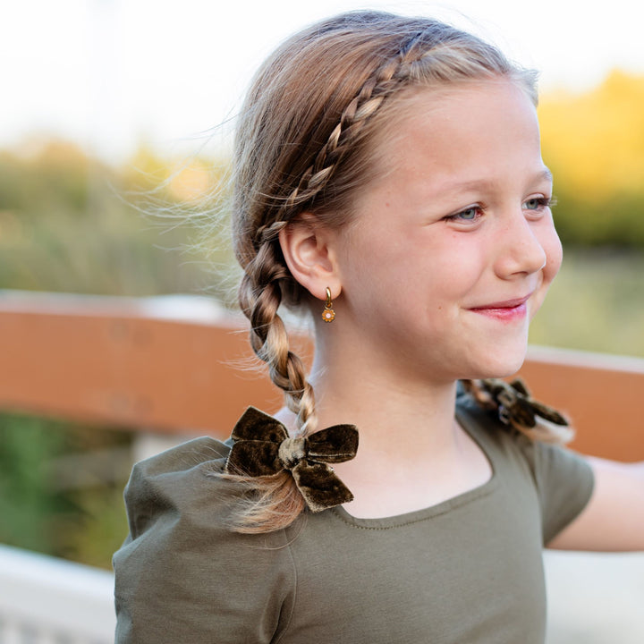 little girl with olive green velvet pigtail bows on braids and matching olive twirl dress