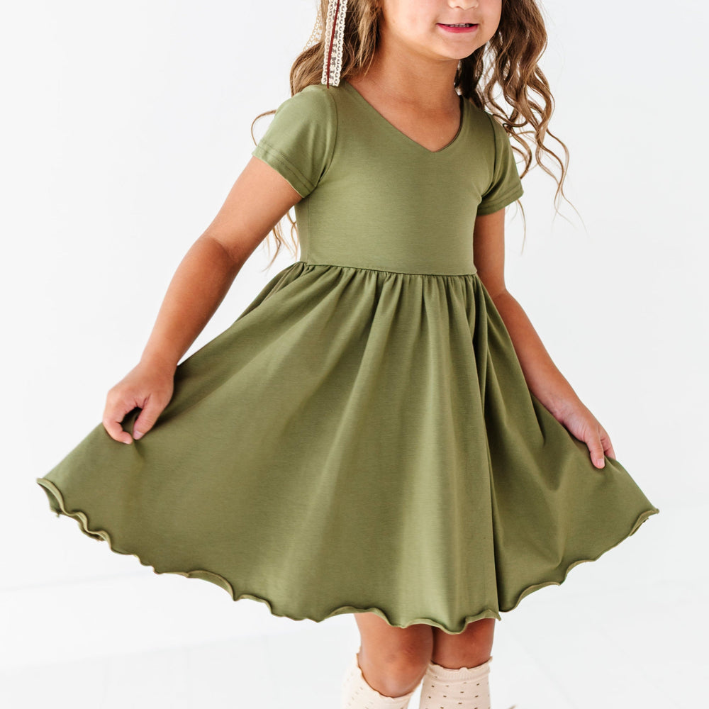 little girl twirling in olive green cotton blend twirl dress with v-neck design and lettuce trim skirt
