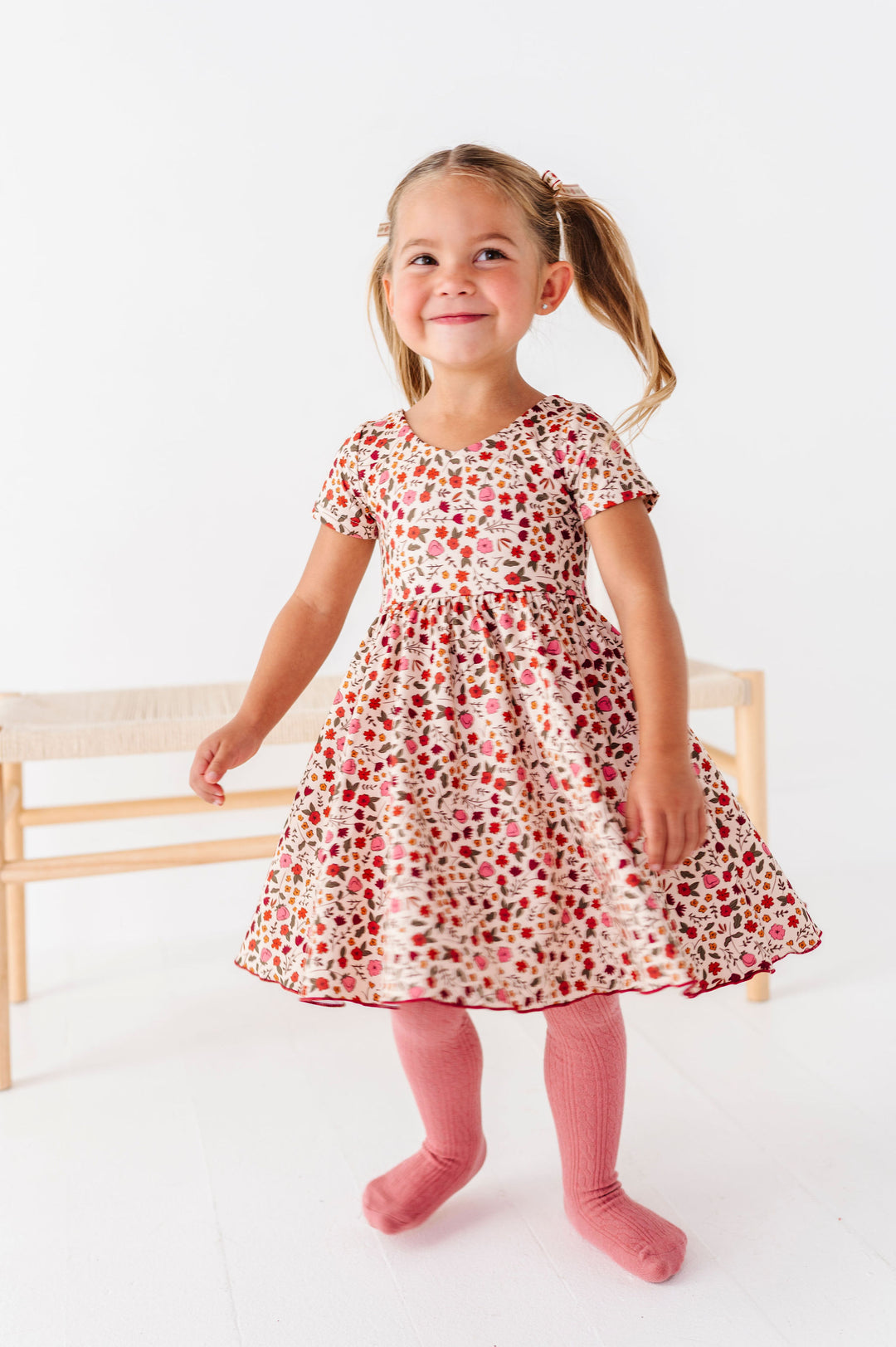 little girl twirling in fall floral printed dress with matching pink tights