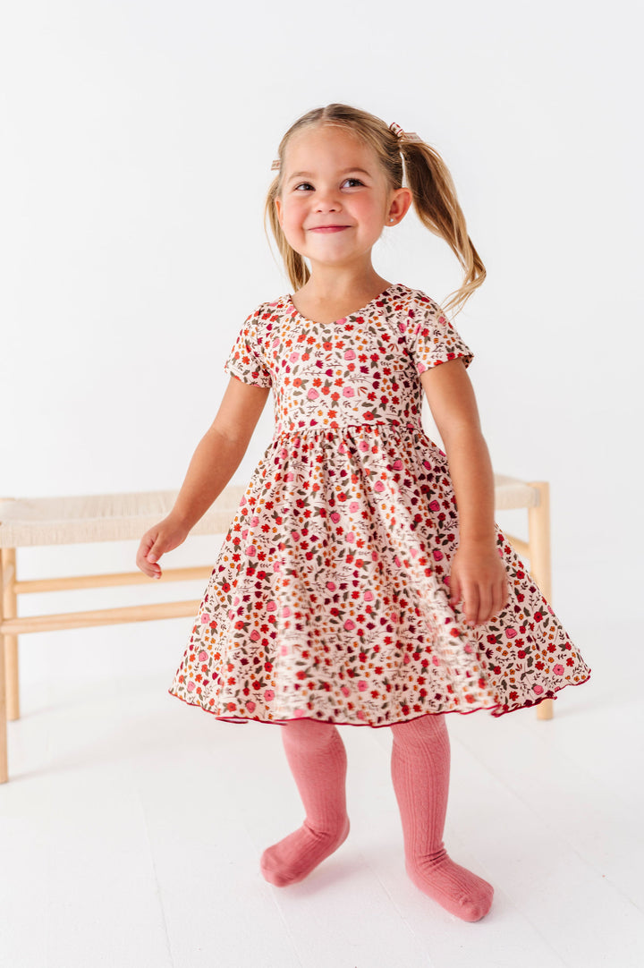 little girl twirling in fall floral printed dress with matching pink tights