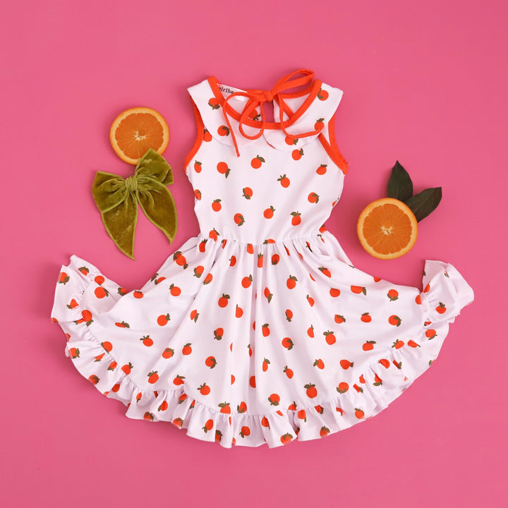 flat lay styled outfit image of orange print tank top dress paired with bright green velvet hair bow