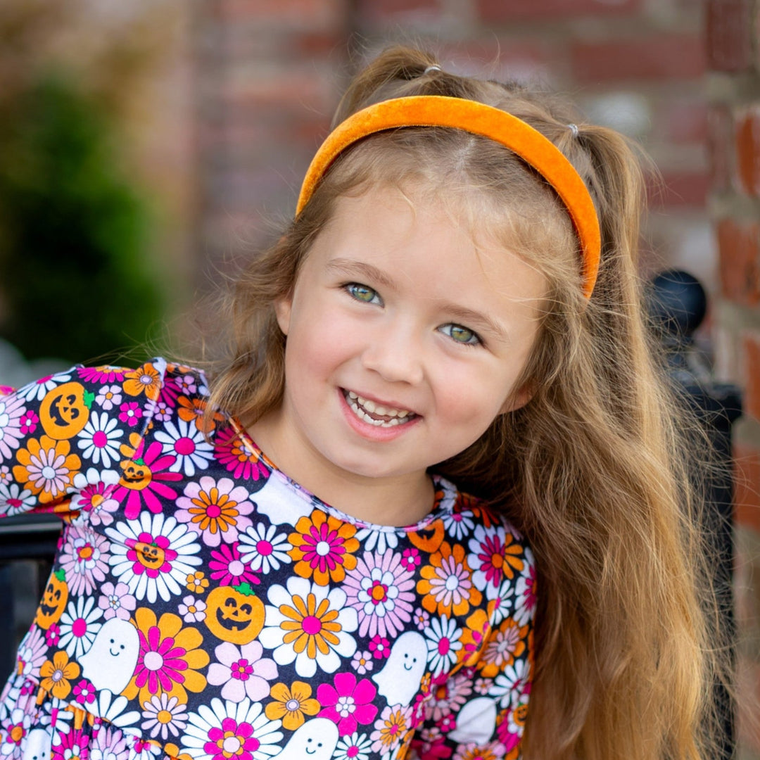 little girl in orange velvet headband and velvet twirl dress with flower, ghosts and pumpkins