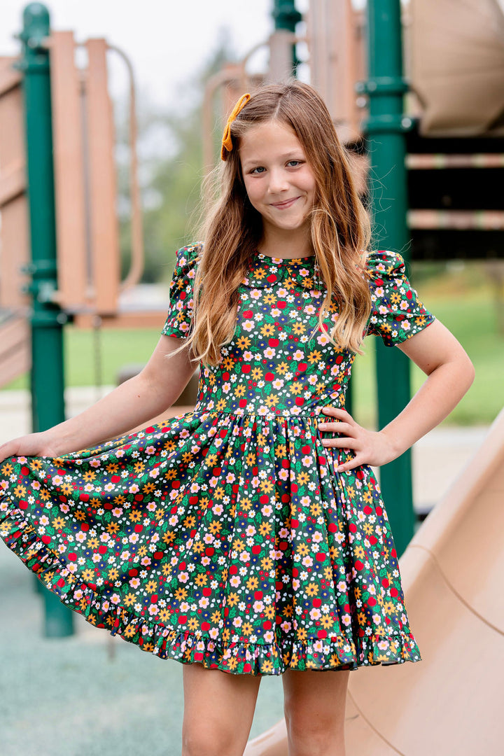 girl on playground in forest green twirl dress with apple and floral print