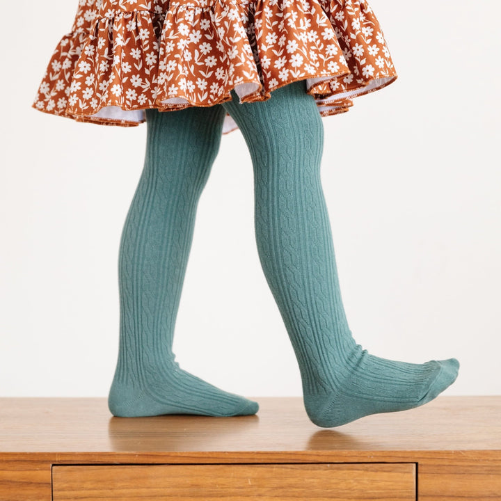 girl in pacific blue cable knit tights and brown floral dress