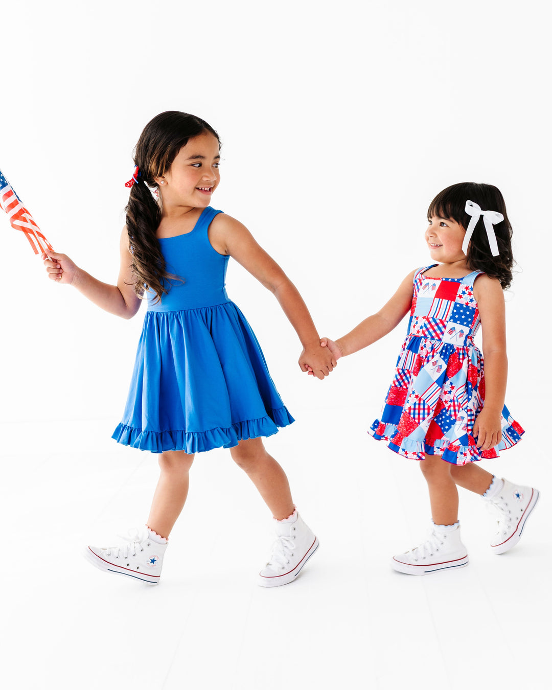 sisters in coordinating royal blue solid and red, white and blue patchwork print twirl dresses for fourth of july