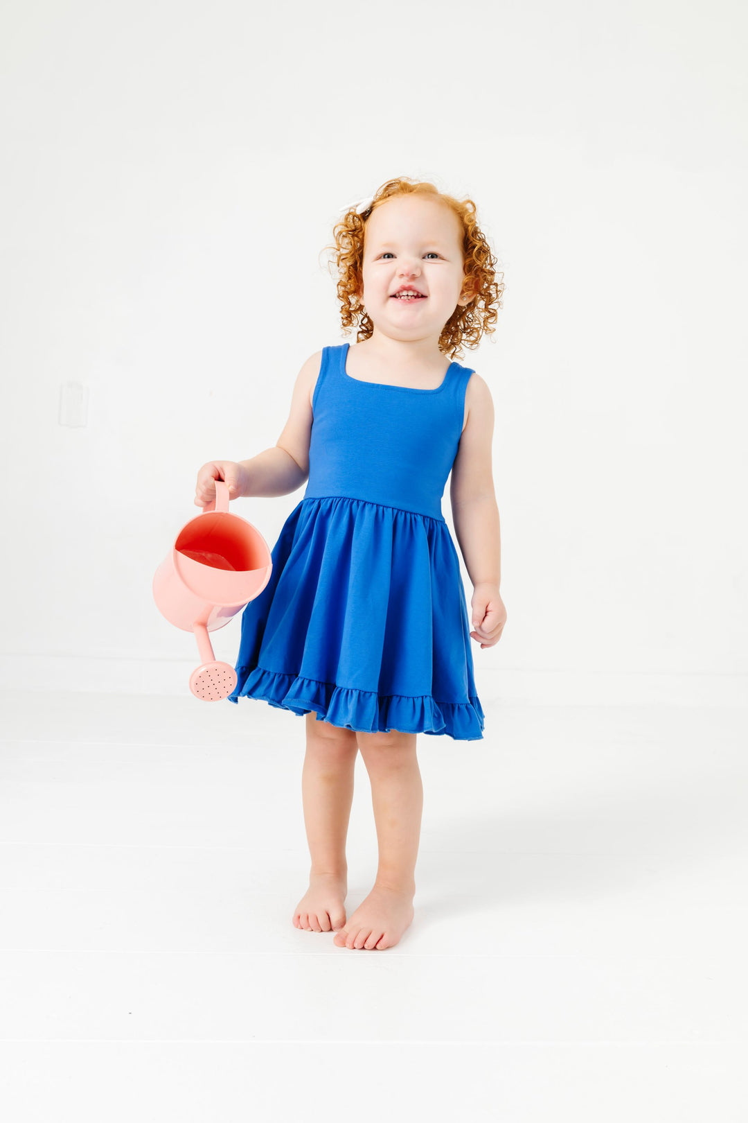 little girl with peach watering can and blue sleeveless cotton blend summer twirl dress