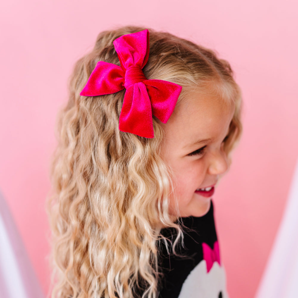 little girl with hot pink velvet hair bow on clip paired with black Halloween sweater with ghost wearing hot pink hair bow to match