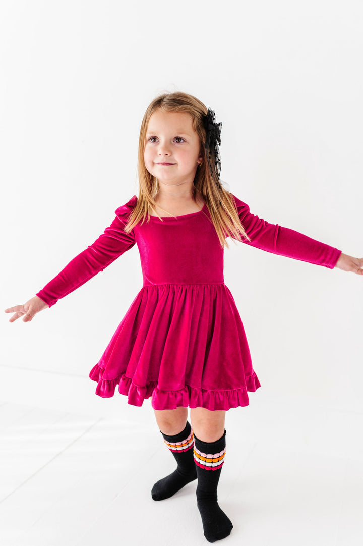 girl wearing pink velvet long sleeve dress and twirling