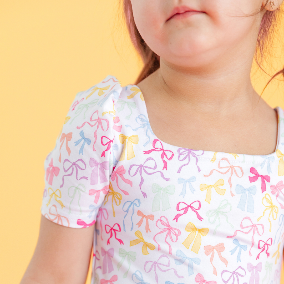 detail photo of little girl wearing white square neck twirl dress with multicolor pastel bow print for spring