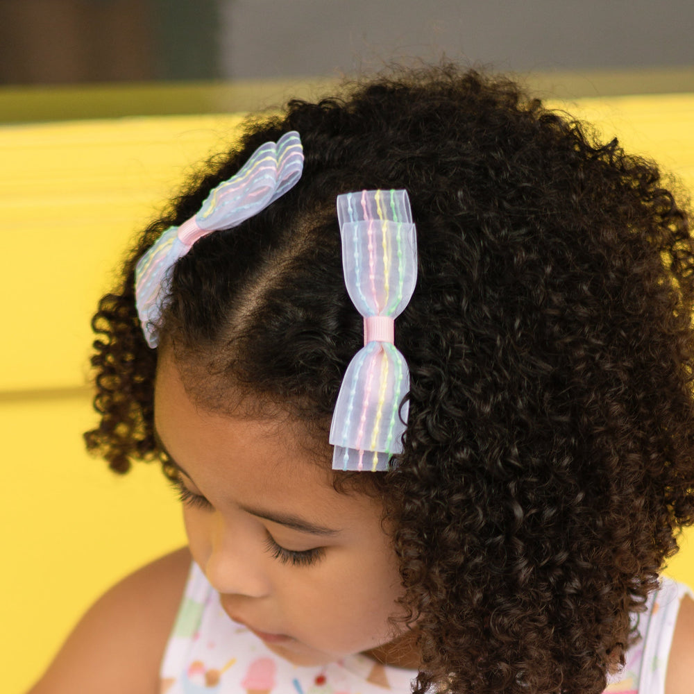 little girl in sheer pigtail bows with embroidered pastel stripes paired with matching ice cream dress