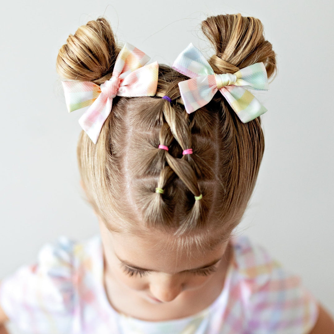 little girl in satin pigtail bows with pastel gingham print to match pastel gingham twirl dress for spring and Easter