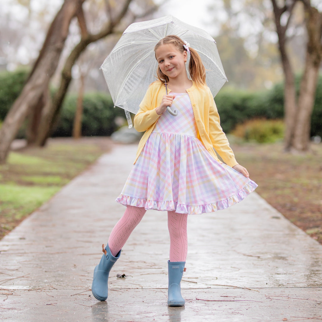 girl in rain in pastel gingham twirl dress, pink tights, yellow cardigan and rain boots