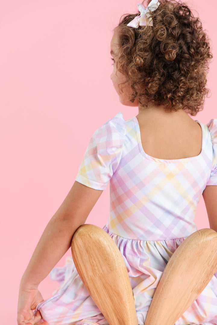 back view of girl in short sleeve square neck spring twirl dress with pastel gingham print on white