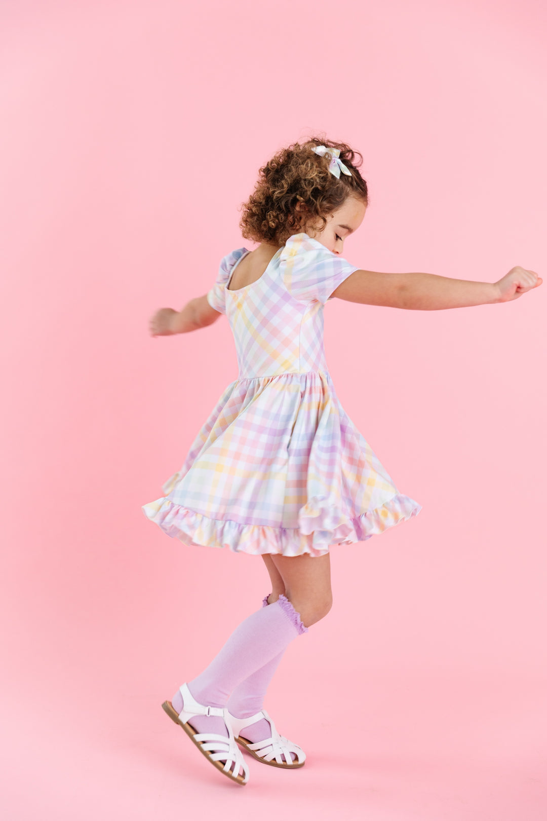 girl wearing short sleeve square neck spring twirl dress with pastel gingham print on white with matching lilac knee highs