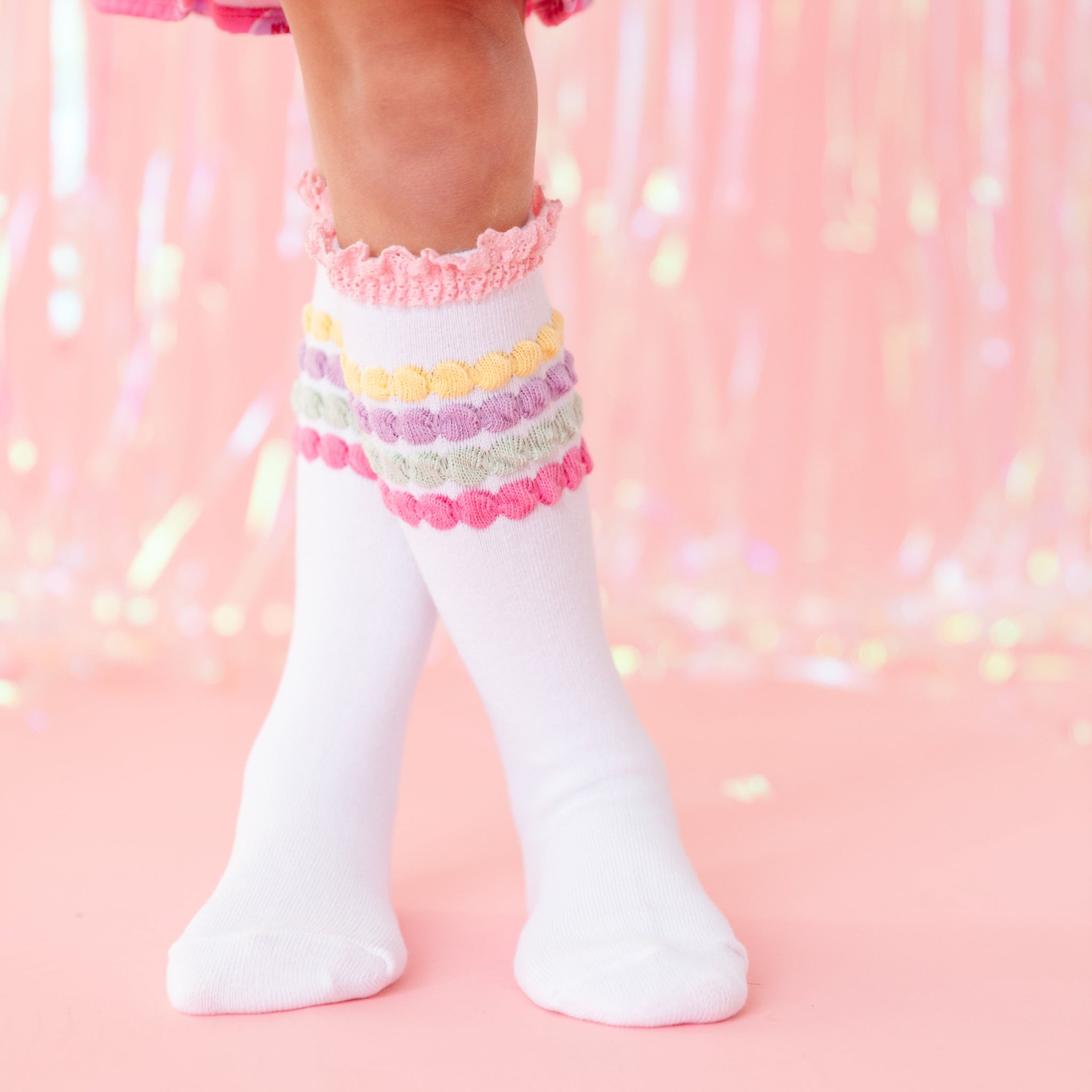 closeup of little girl in white knee high socks with pastel bubble stripe and pink lace trim