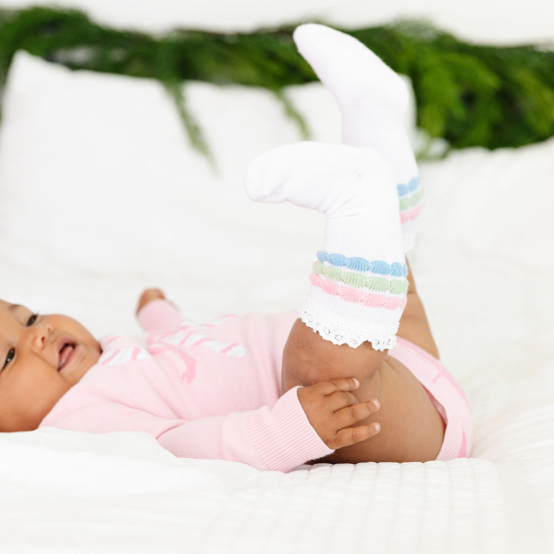 baby girl in white knee highs with pastel pink, mint and blue raised stripes to match pink candy cane sweater