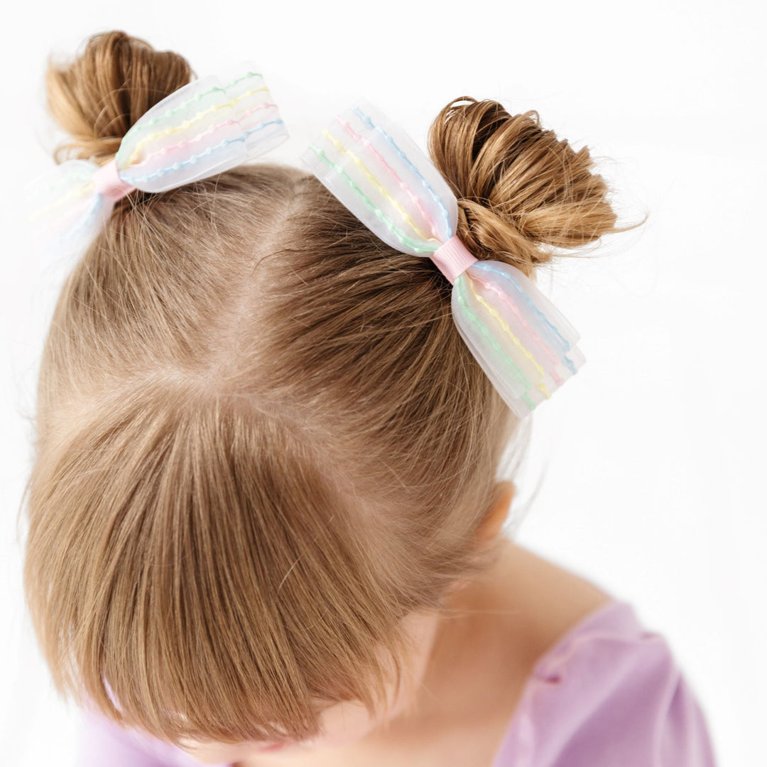 little girl in sheer pigtail bows with embroidered pastel stripes paired with spring purple twirl dress