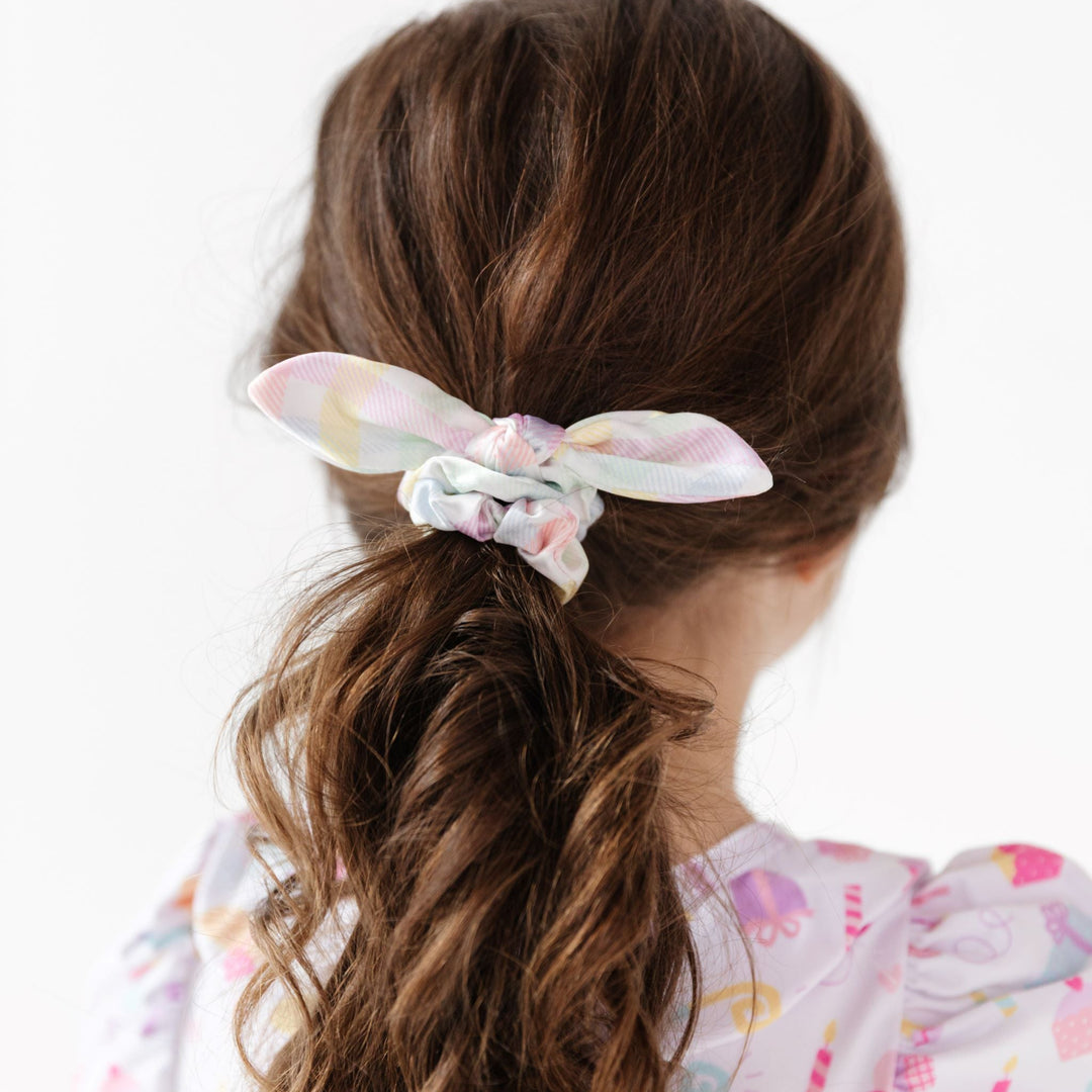 little girl in ponytail styled with satin bow scrunchie in pastel gingham print for birthday and easter outfits