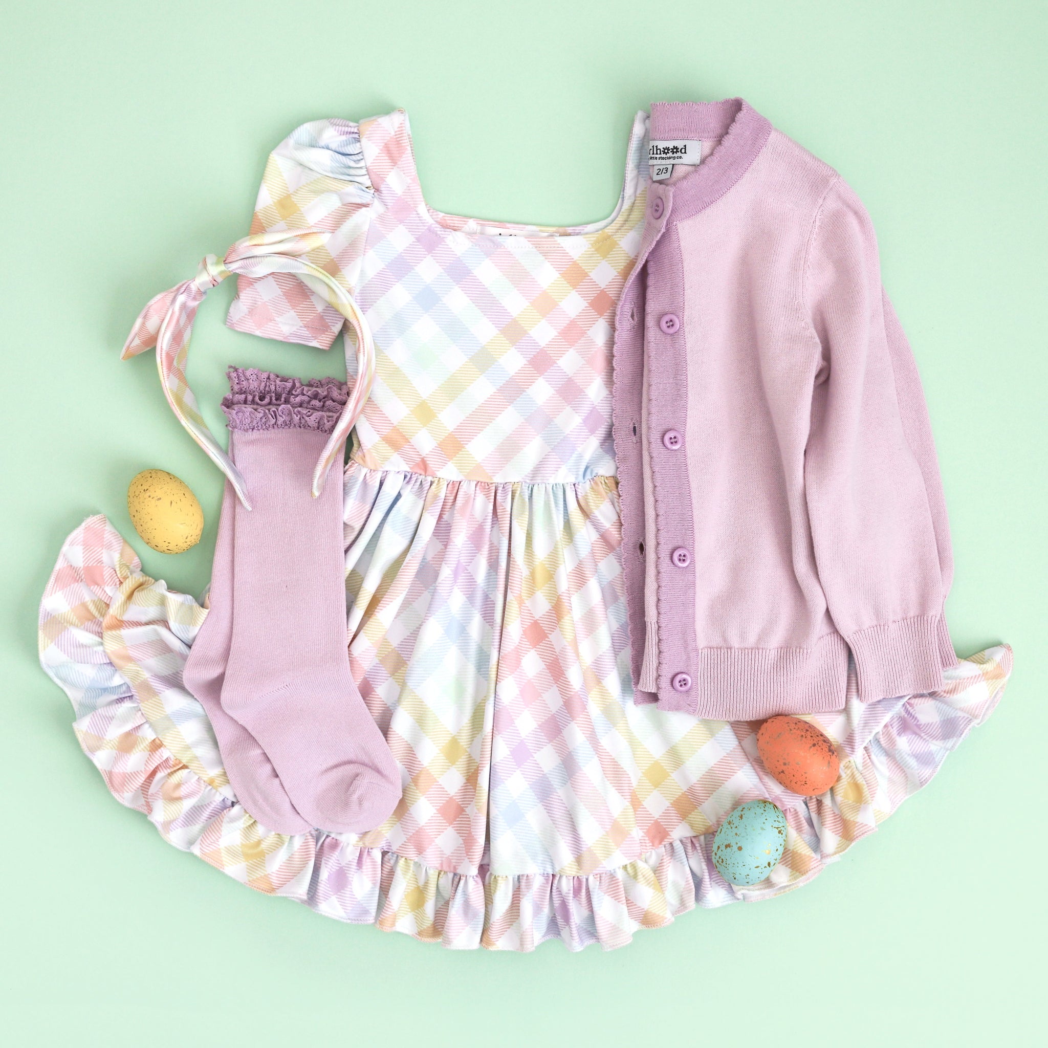 girl's Easter outfit featuring square neck pastel gingham twirl dress and matching satin headband with purple sweater and knee highs