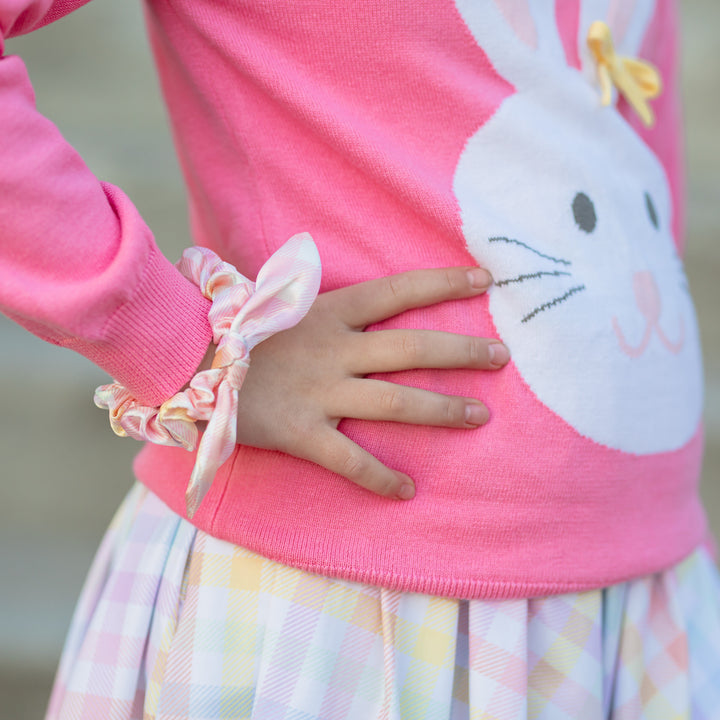 little girl wearing satin scrunchie on wrist with pastel gingham pattern and matching pastel gingham twirl dress