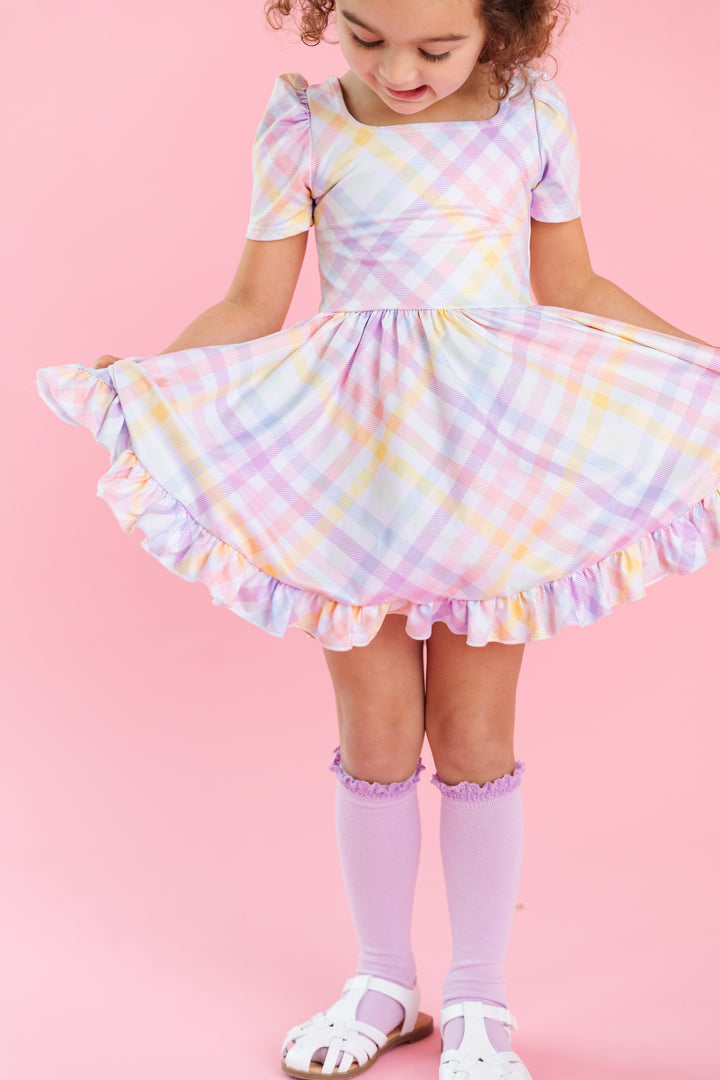 girl wearing short sleeve square neck spring twirl dress with pastel gingham print on white with matching lilac knee highs