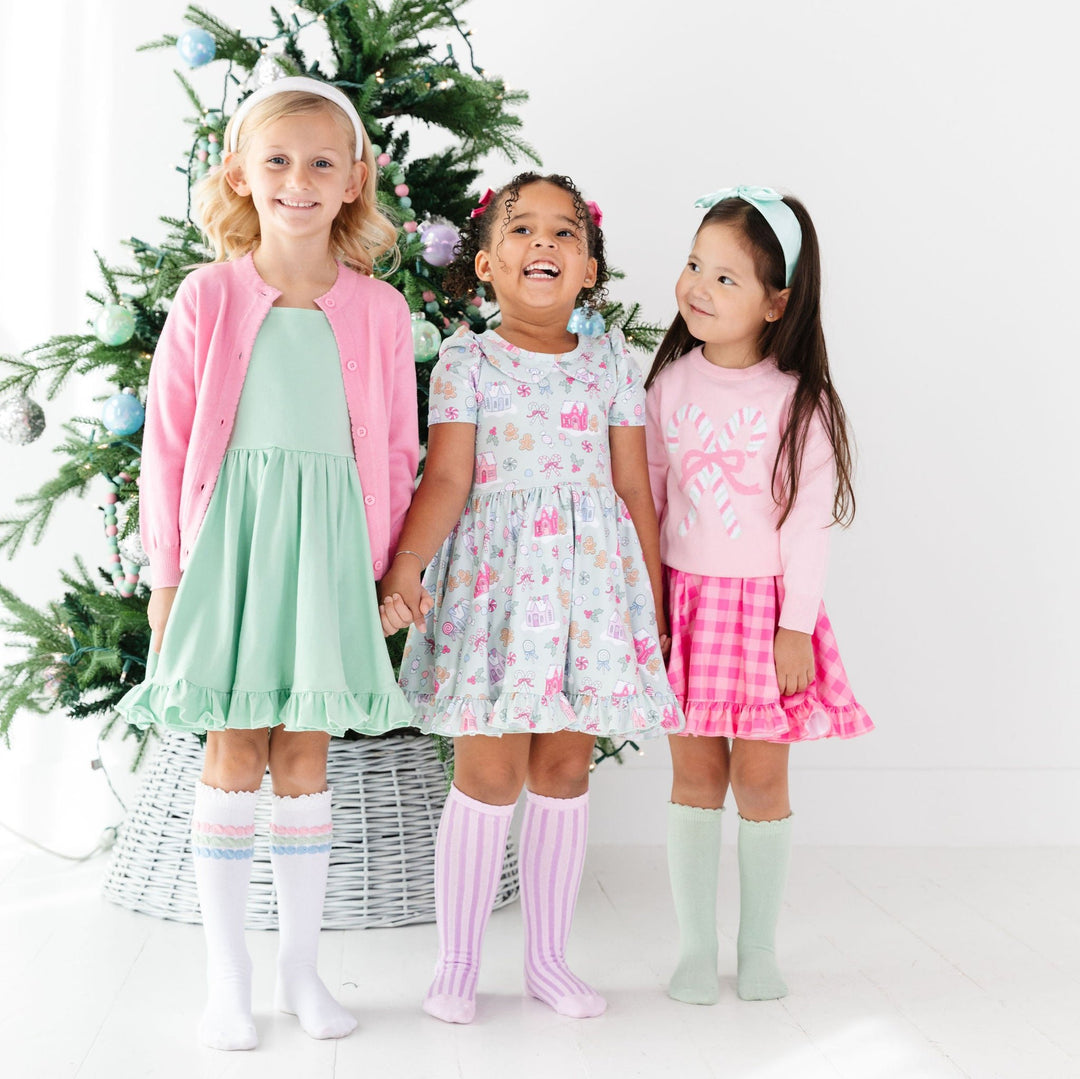 girls in front of christmas tree wearing pastel christmas outfits mint pink purple