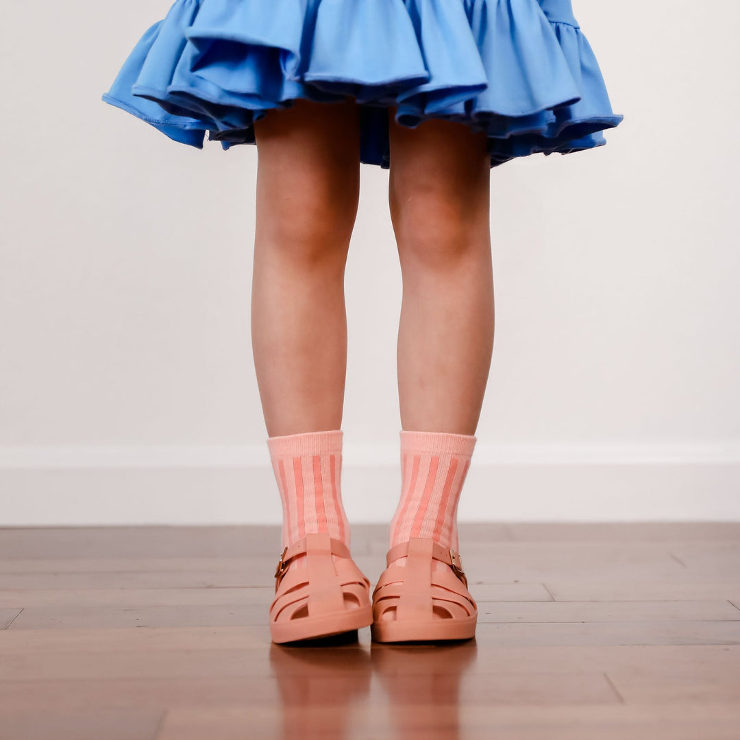 peach and pink vertical striped midi socks on little girl in blue ruffle twirl dress