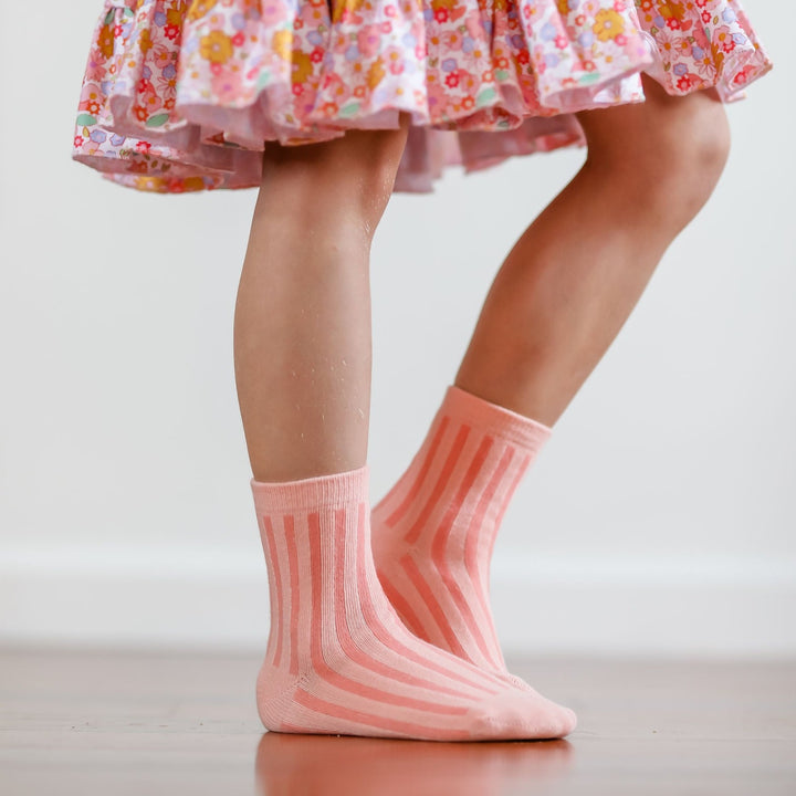 little girl standing in peachy pink striped midi socks and floral spring twirl dress