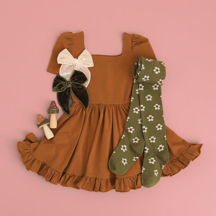 flatlay of girls outfit of pecan twirl dress and olive floral tights and velvet bows